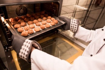 a person taking pastries out of an oven