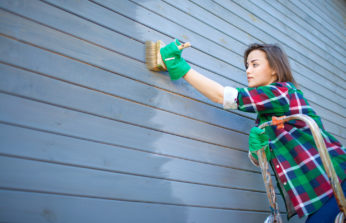woman painting wooden wall