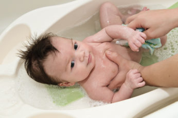 infant being bathed in plastic tub