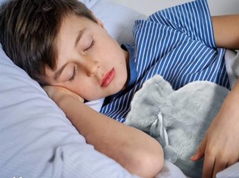 a sleeping boy holding a bed warmer